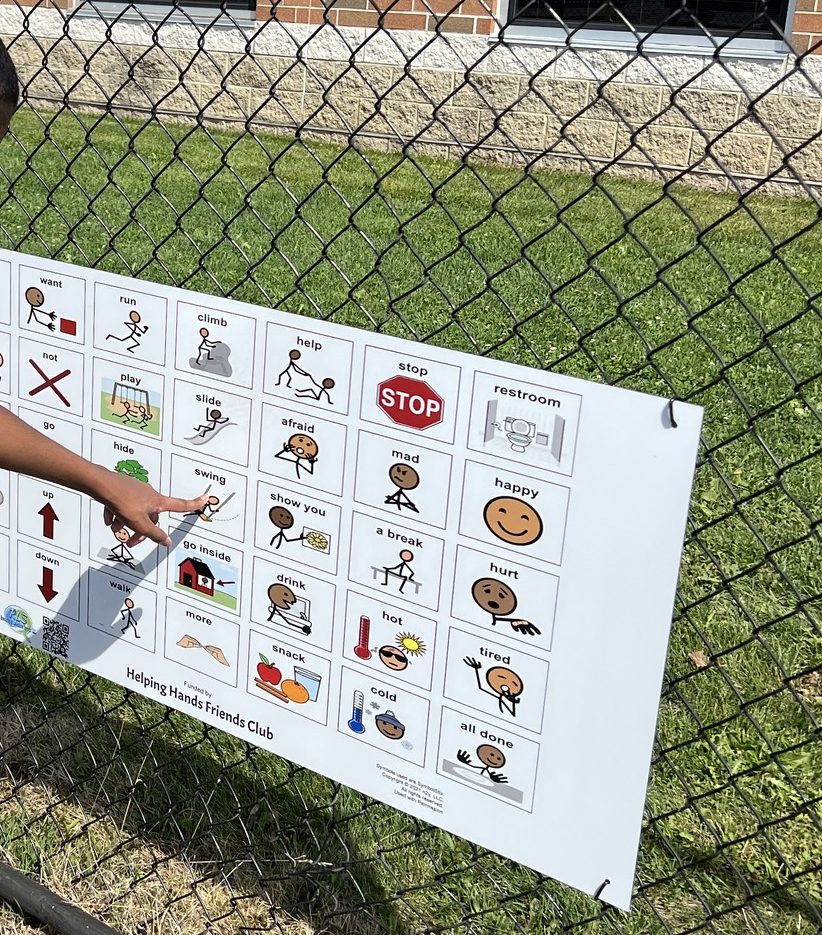 student pointing to playground communication board